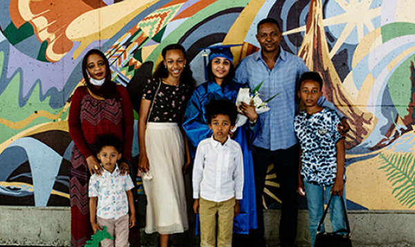 Graduate with family in front of mural