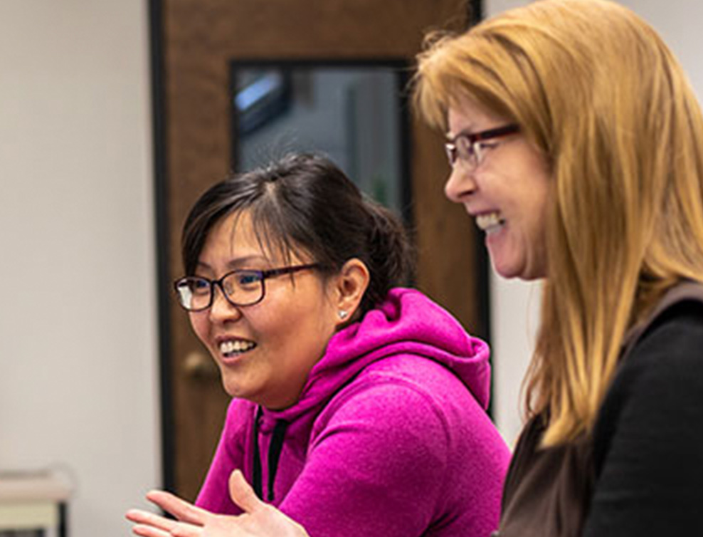 Student sits with instructor at computer.