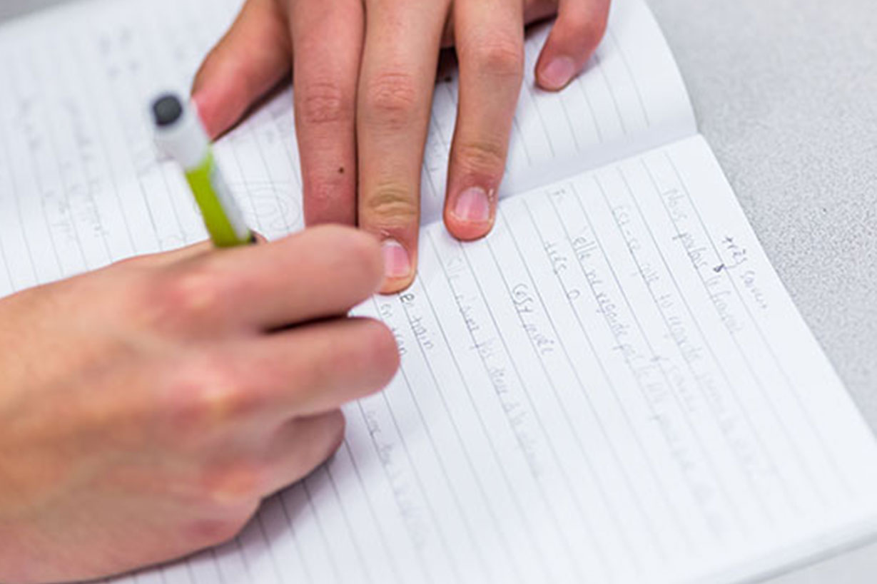 hands writing on a piece of white paper