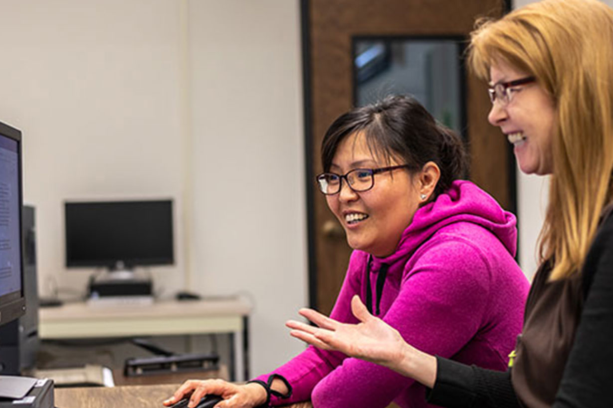 2 staff members sit at computer.