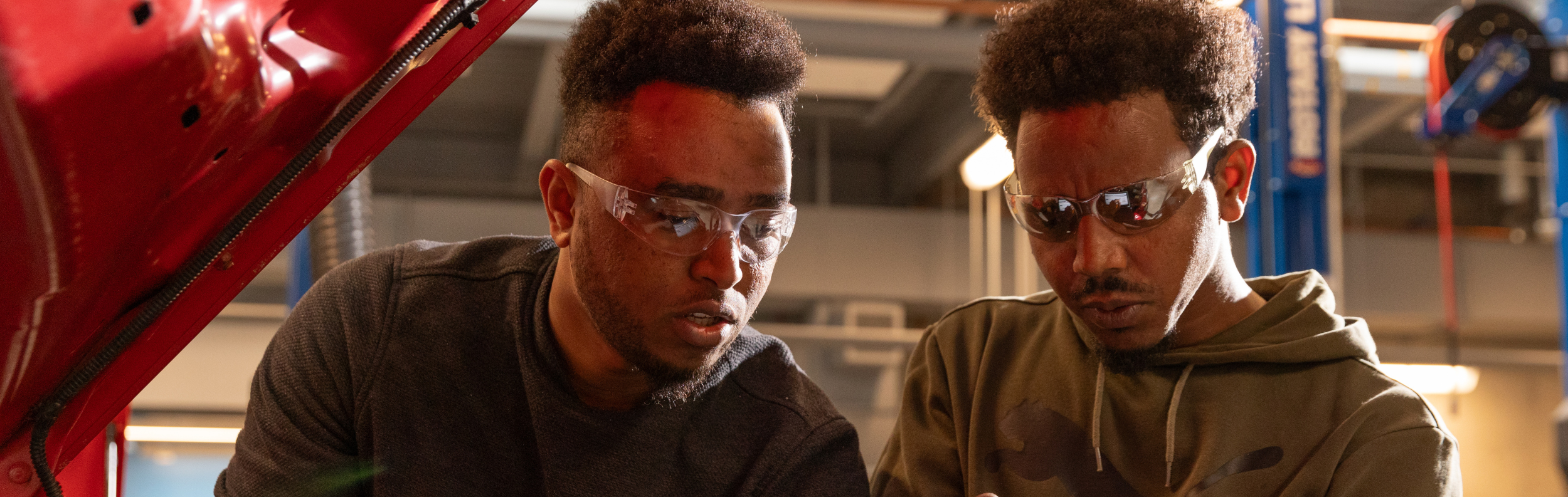  Two Automotive students examine a car engine 
